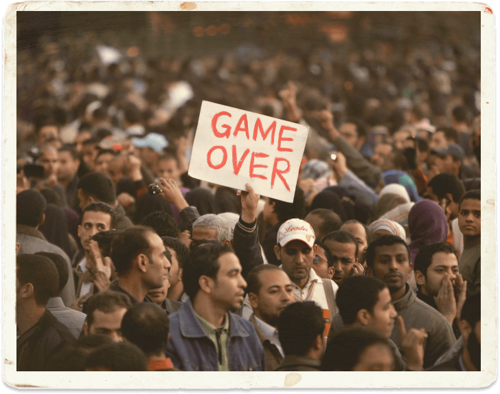 Фото человека в толпе с плакатом GAME OVER
